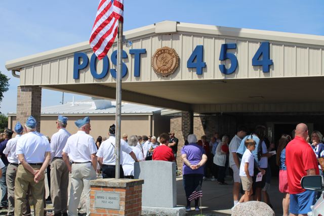 The entrance of VFW Post 454 with the flag flying and a crowd gathered
