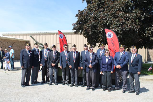A group of veterans in blazers and caps posed together outside VFW Post 454