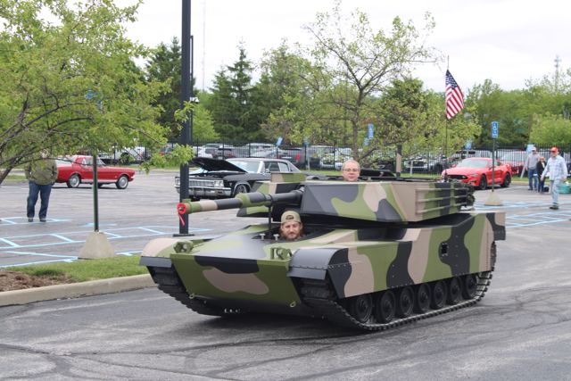 Lil Abe driving through a parking lot with a young visitor riding in the turret