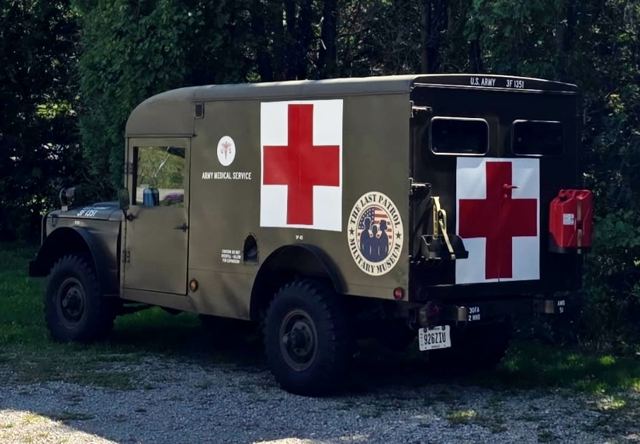 Rear three-quarter view of the M725 ambulance showing the red cross and jerry can