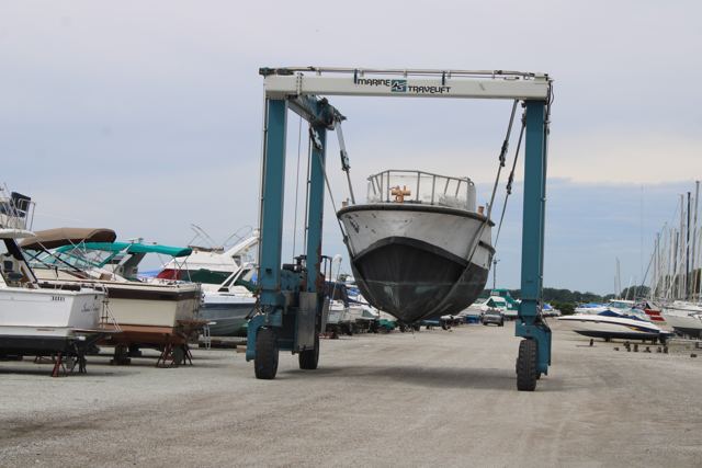 A marina travel lift carrying MLB 44334 across the boatyard