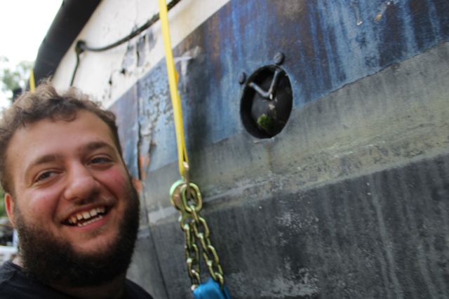 A smiling volunteer working beneath the hull of MLB 44334