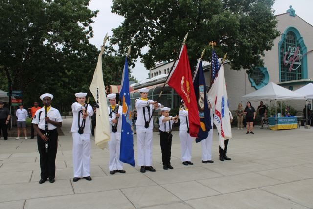 Sea Cadet color guard in dress whites carrying service flags