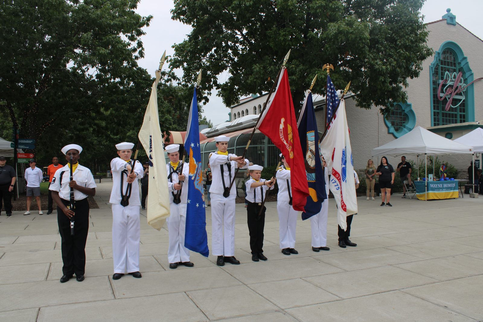 Sea Cadet color guard in dress whites carrying the service flags