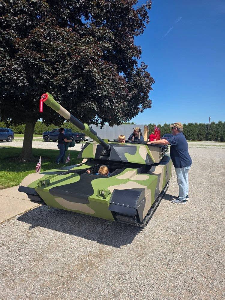 Young visitors exploring Lil Abe, the half-scale tank replica, with a volunteer alongside