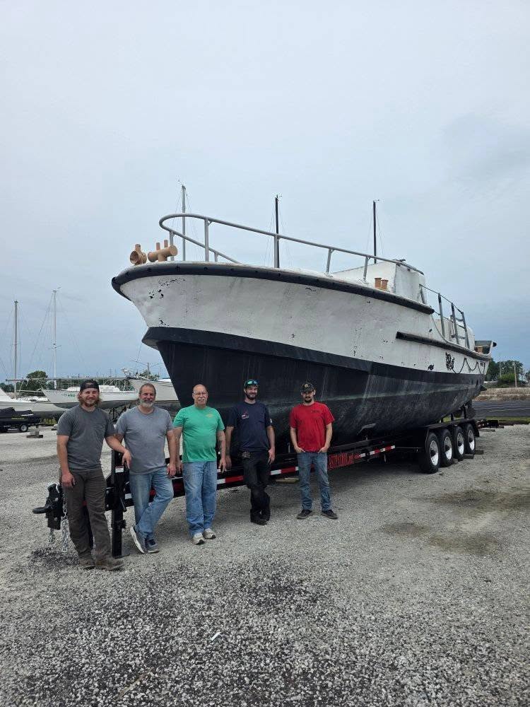 Five volunteers standing in front of MLB 44334 on its transport trailer